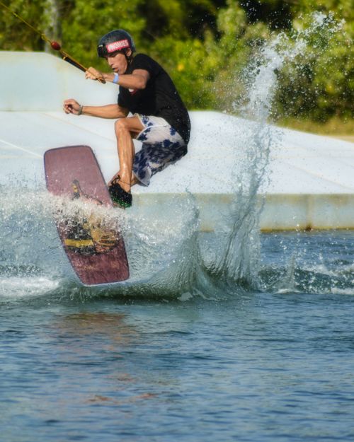 Free Young man performing a trick on a wakeboard, splashing water in Phuket, Thailand. Stock Photo