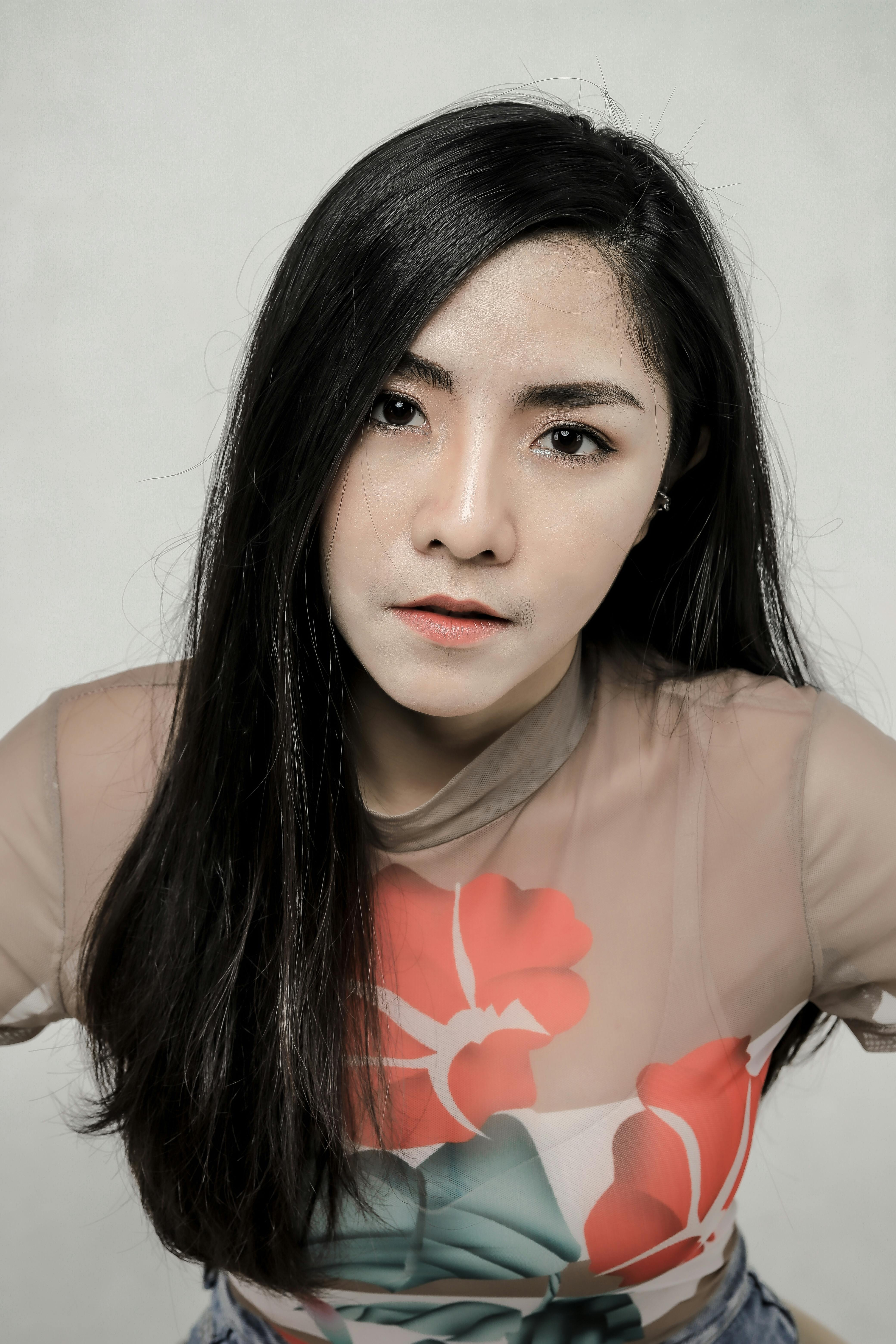 Close-up portrait of a woman with long hair wearing a floral mesh top, showing contemporary fashion 