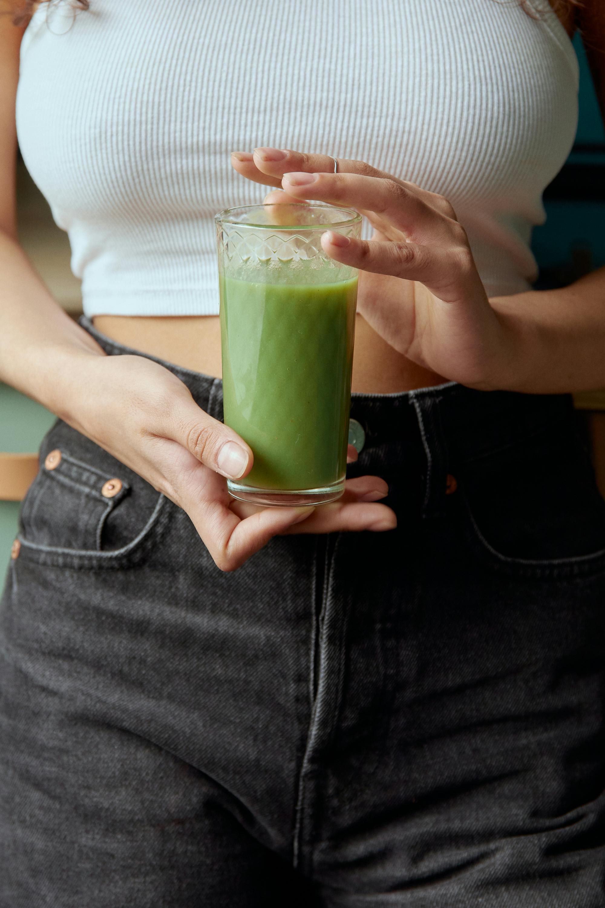 Woman in White Long Sleeve Shirt Holding Clear Drinking Glass With Green Liquid