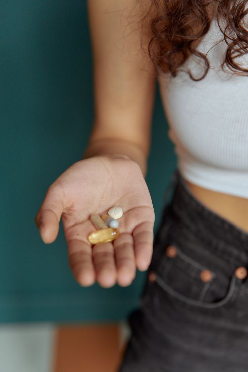 Free Person's hand holding different pills, highlighting medication and health care. Stock Photo