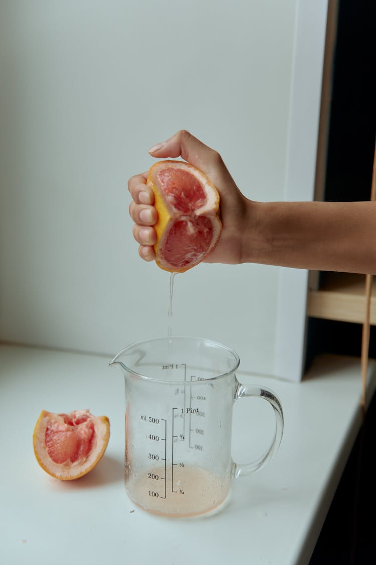 A Person's Hand Squeezing A Grapefruit