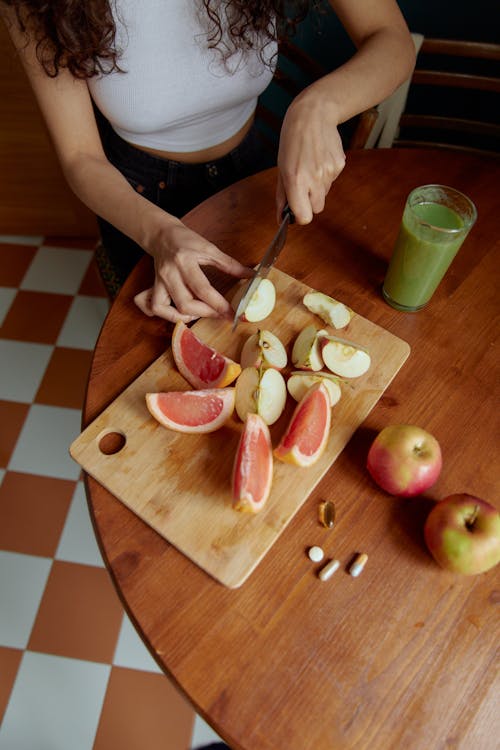 Person Slicing Apple on Chopping Board