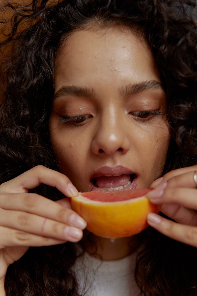 A Woman Eating A Slice Of Grapefruit