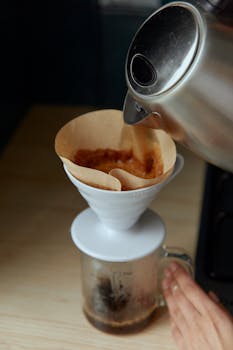 Hot water being poured over ground coffee in a filter cone for brewing.