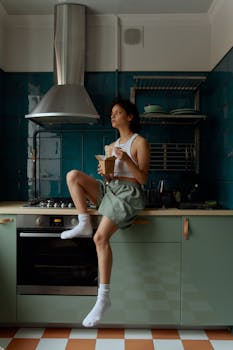 Woman in a tank top enjoying a meal on a kitchen counter, conveying a casual indoor ambiance.