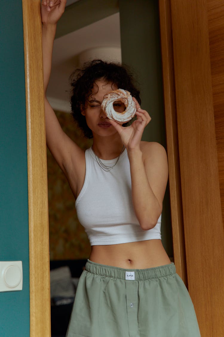 Woman Standing On A Doorway Holding A Donut