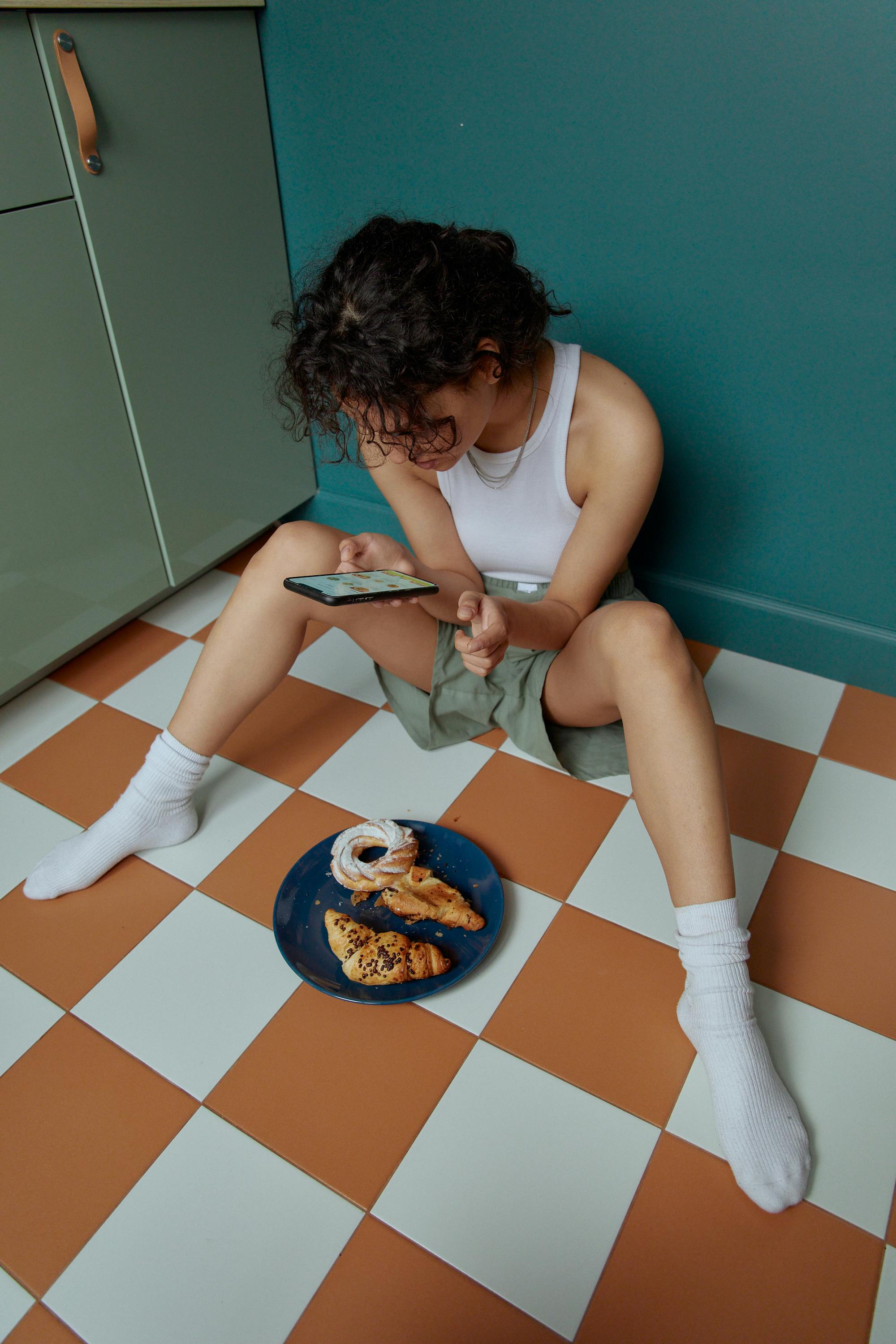 Woman in White Tank Top and White Pants Sitting on Blue and White Checkered Floor