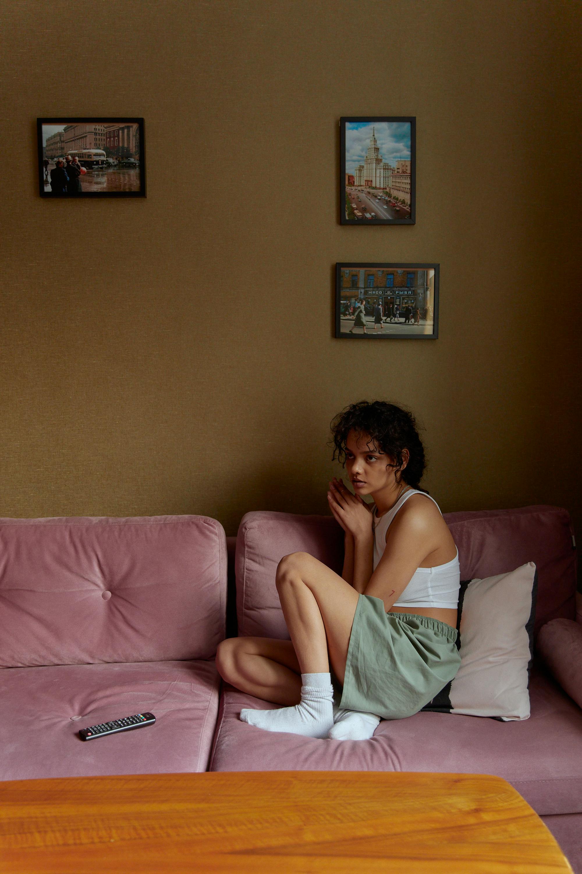 woman in white tank top sitting on a pink sofa