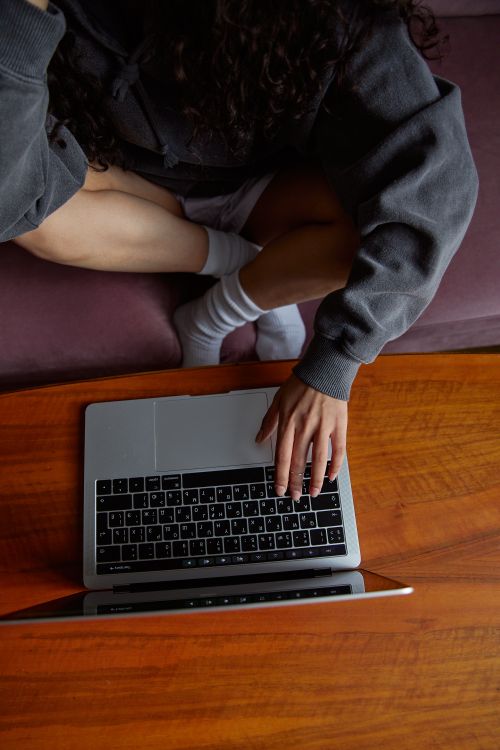 Free A person using a laptop on a wooden table, perfect for remote work or student life. Stock Photo