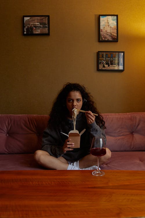 Woman in Black Long Sleeve Shirt Sitting on Red Couch