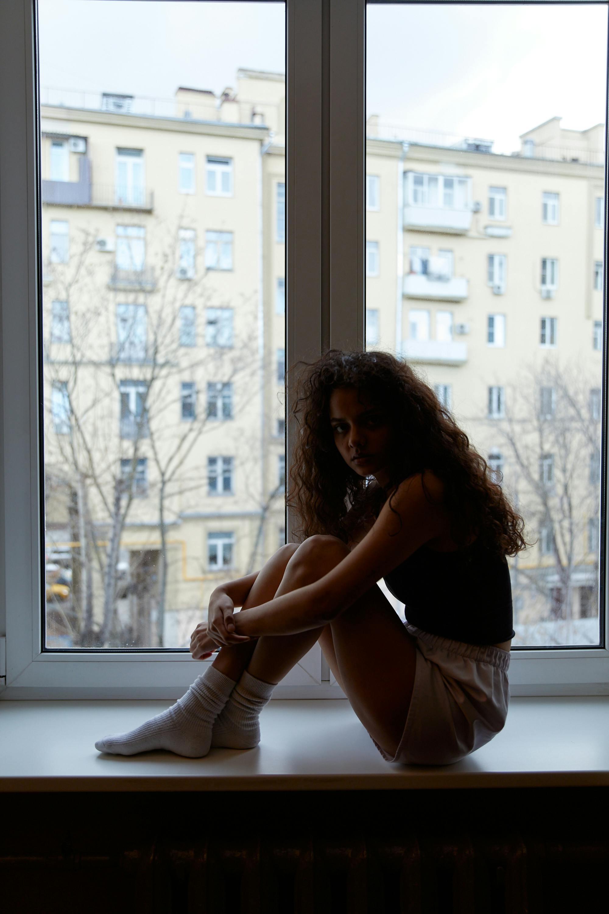 Woman in Black Tank Top and White Skirt Sitting on Window