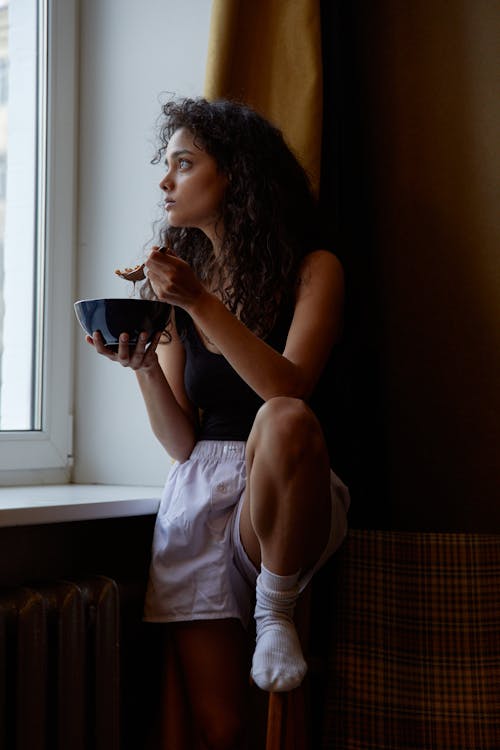 A Woman Eating Alone While Looking Outside