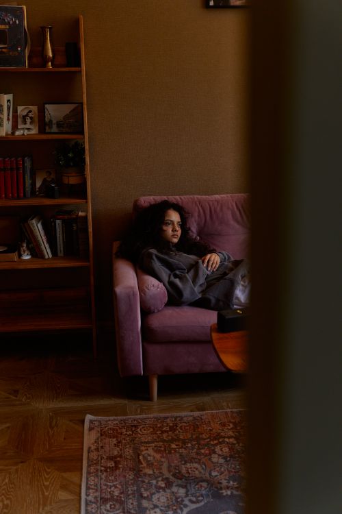 Free A contemplative woman lying on a couch in a cozy, dimly lit room. Stock Photo