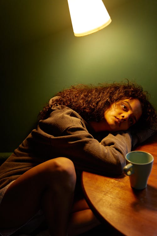 Woman in Gray Long Sleeve Shirt Lying on Bed