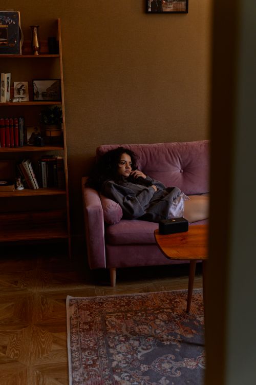 Free Moody scene of a woman lounging on a couch in a cozy, warm-toned room. Stock Photo