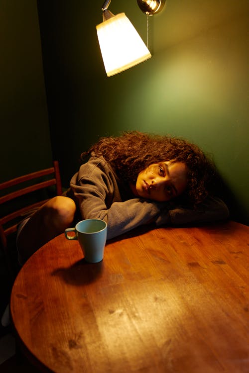Woman in Gray Long Sleeve Shirt Lying on Brown Wooden Floor
