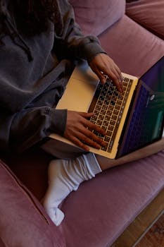 Person working remotely on a laptop from a cozy indoor sofa, showcasing technology and lifestyle.