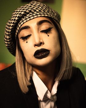 Close-up portrait of a woman wearing gothic makeup and a beret, exuding style and elegance.