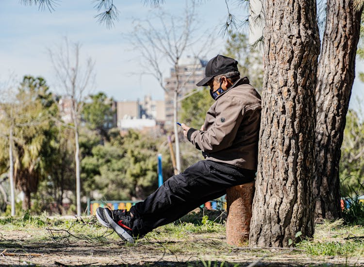 Old Man Sitting Near Tree In Park