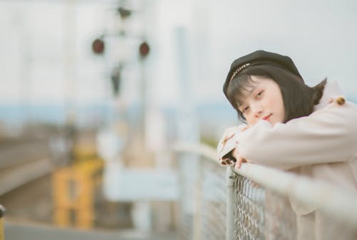 Selective Focus Photo of a Beautiful Woman Leaning on a Railing