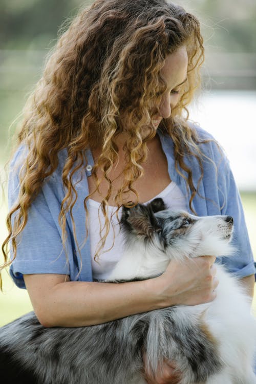 Smiling woman with curly hair stroking fluffy dog