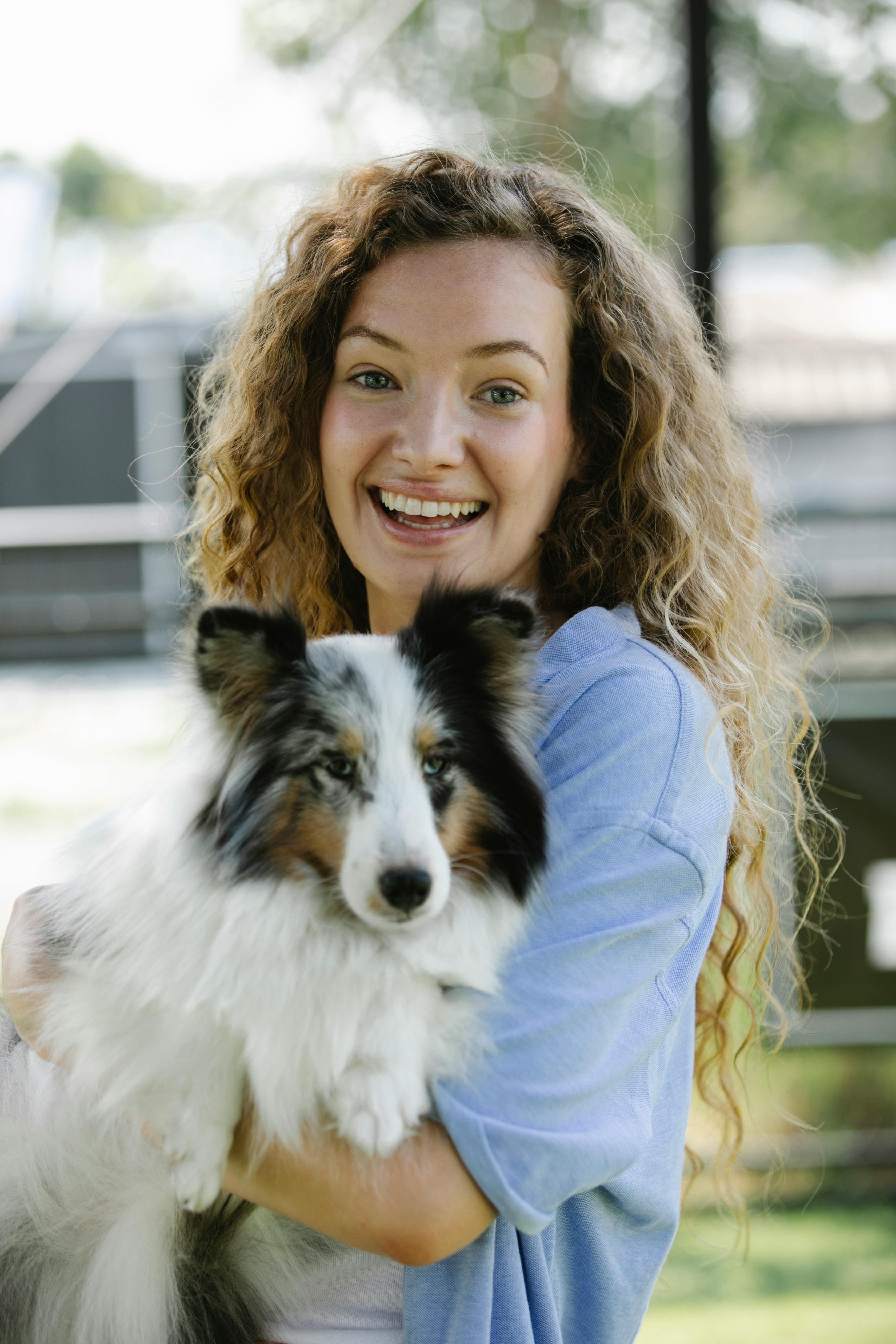 Smiling woman embracing Shetland Sheepdog in courtyard