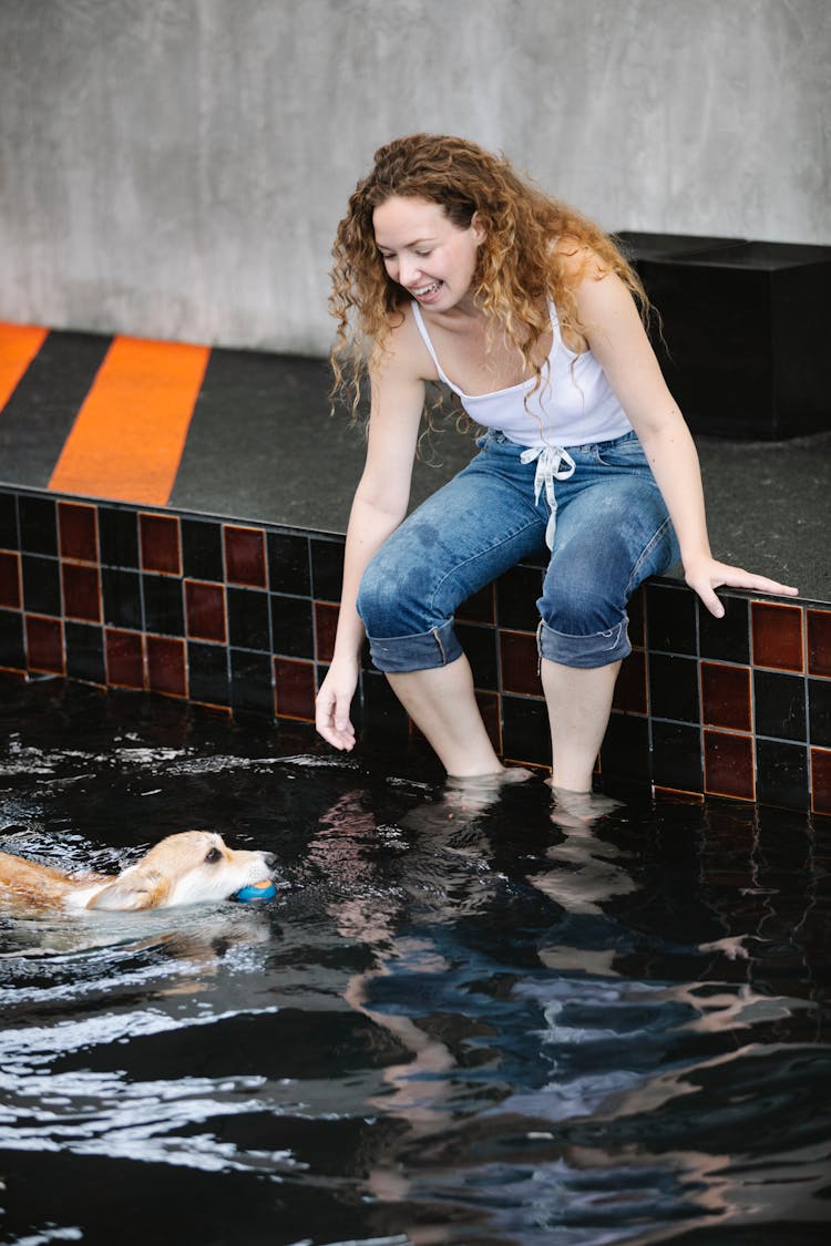 Content Woman Playing With Purebred Dog Swimming In Pool