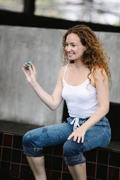 Cheerful woman with ball resting on poolside