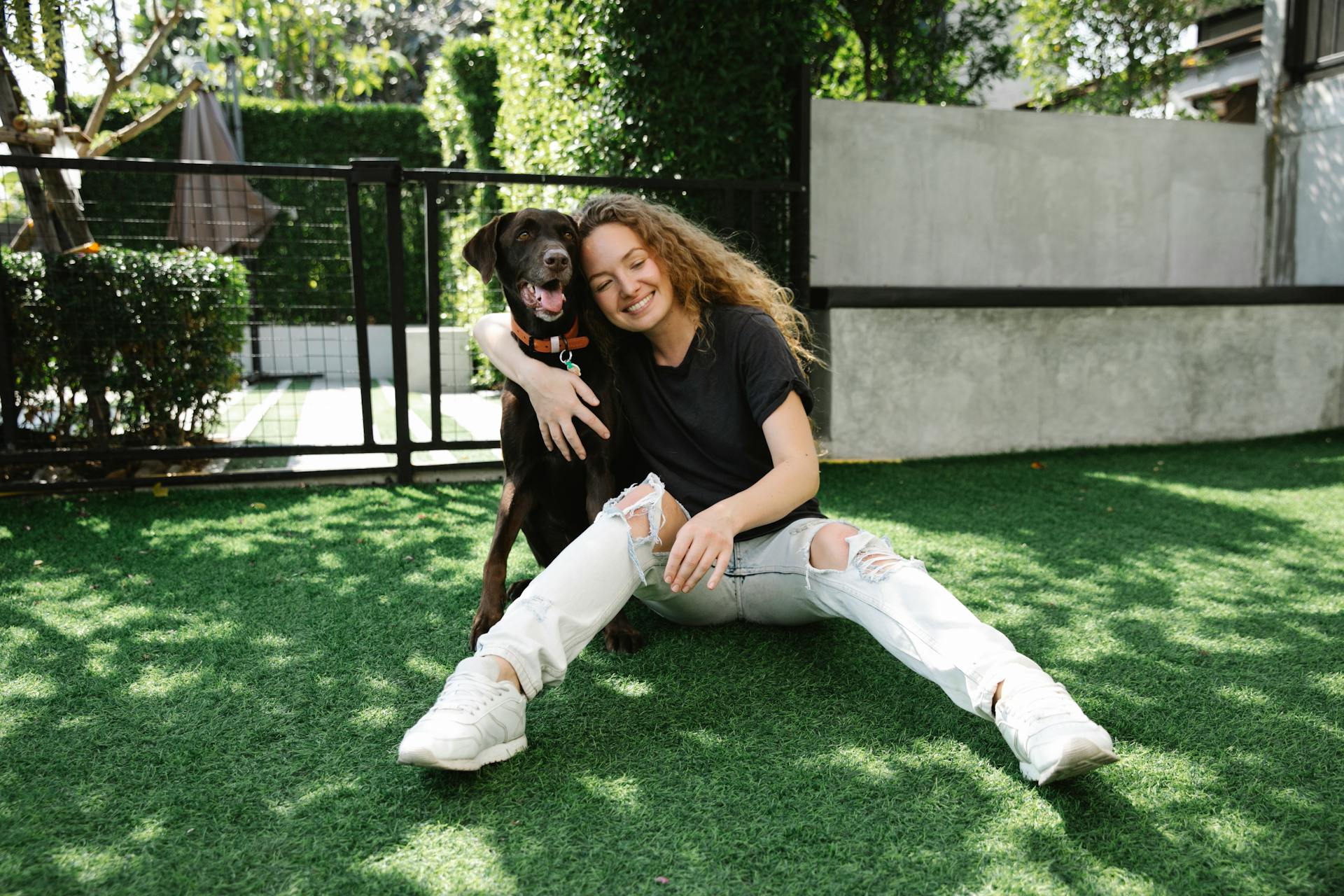 Happy woman embracing hunting dog on lawn in patio