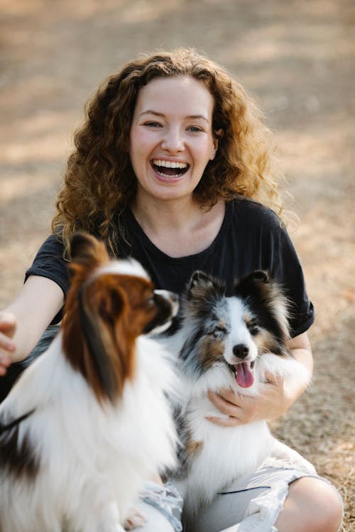 Free A Happy Woman Posing with Two Dogs Stock Photo