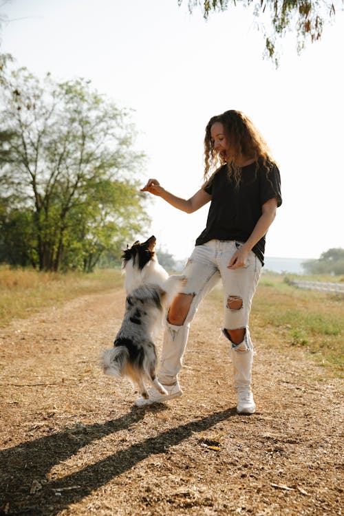 Молодая женщина, играющая со своей собакой