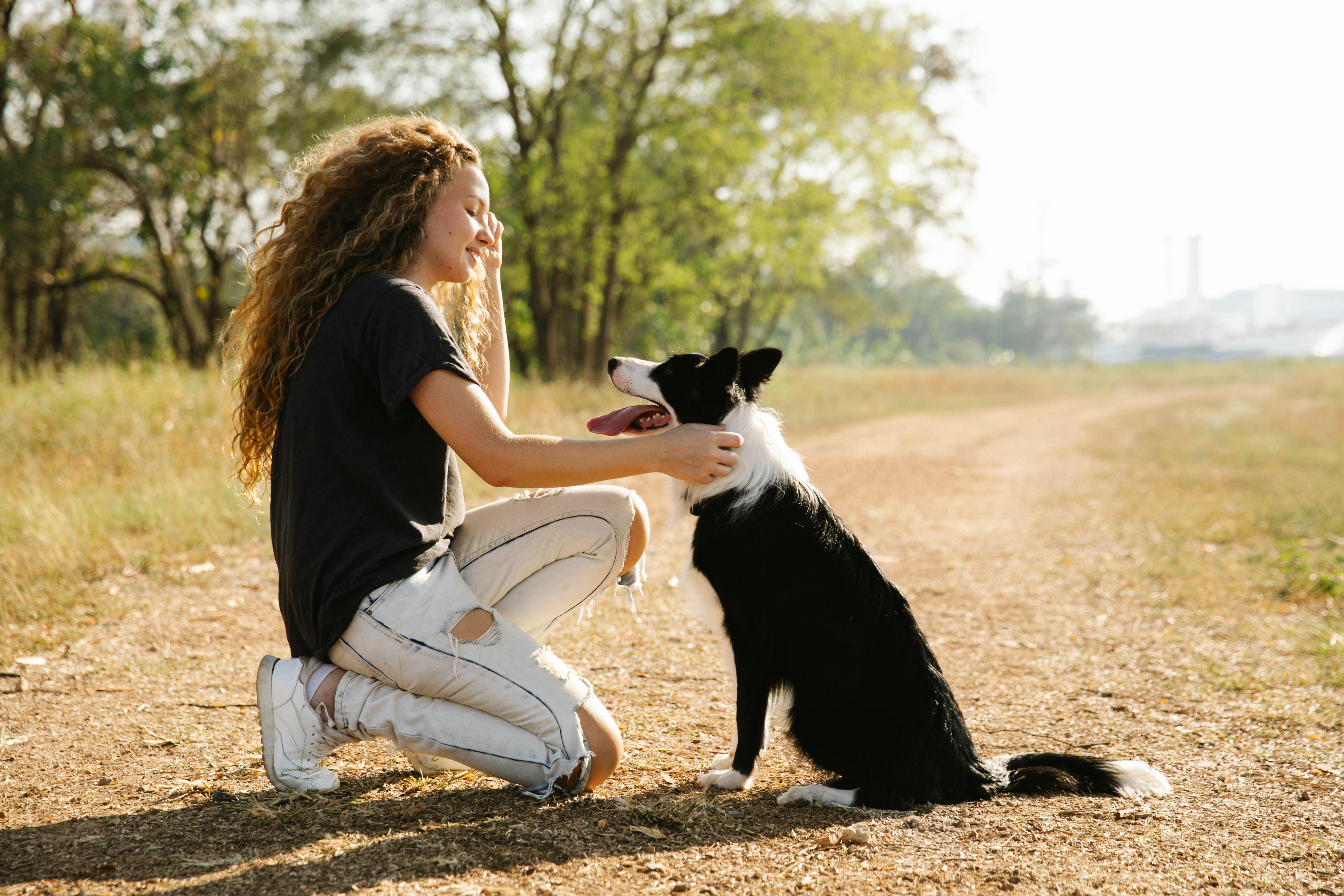 a young woman and a dog on a dirt road