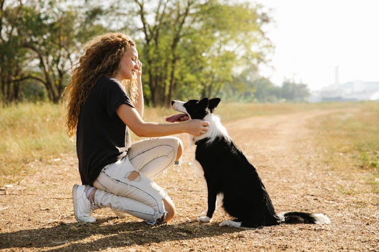 A Young Woman And A Dog On A Dirt Road 