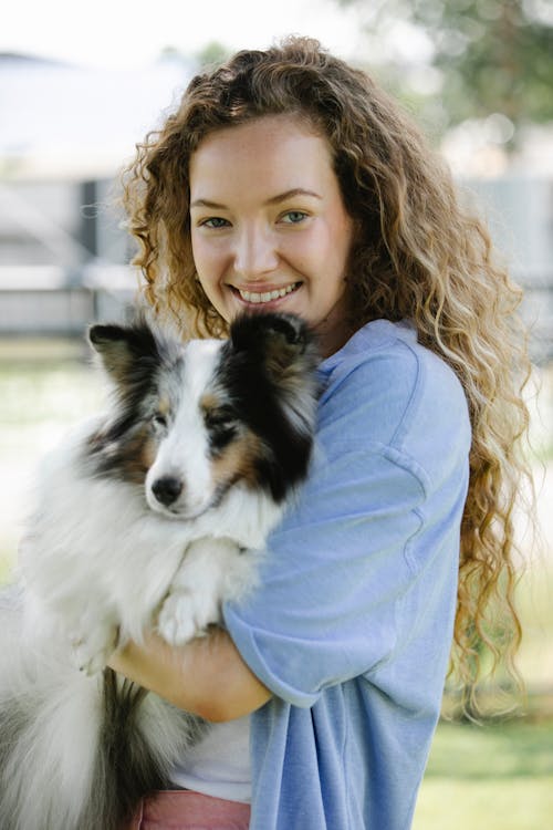Cheerful owner embracing Collie in daytime outdoors
