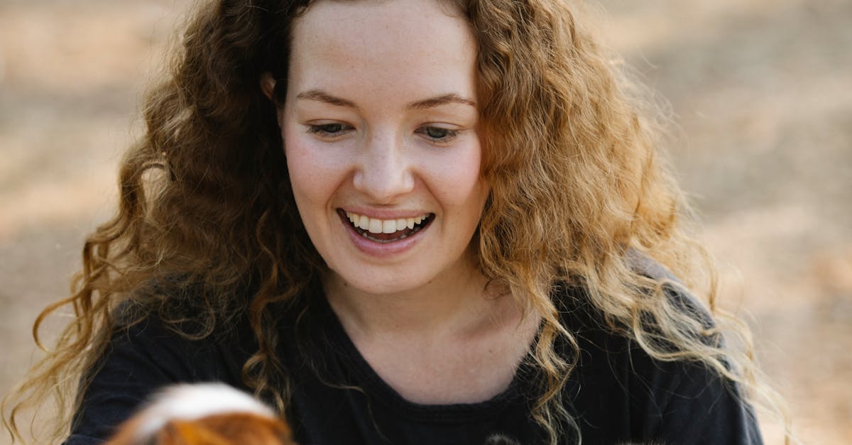 Happy woman caressing purebred dogs in nature