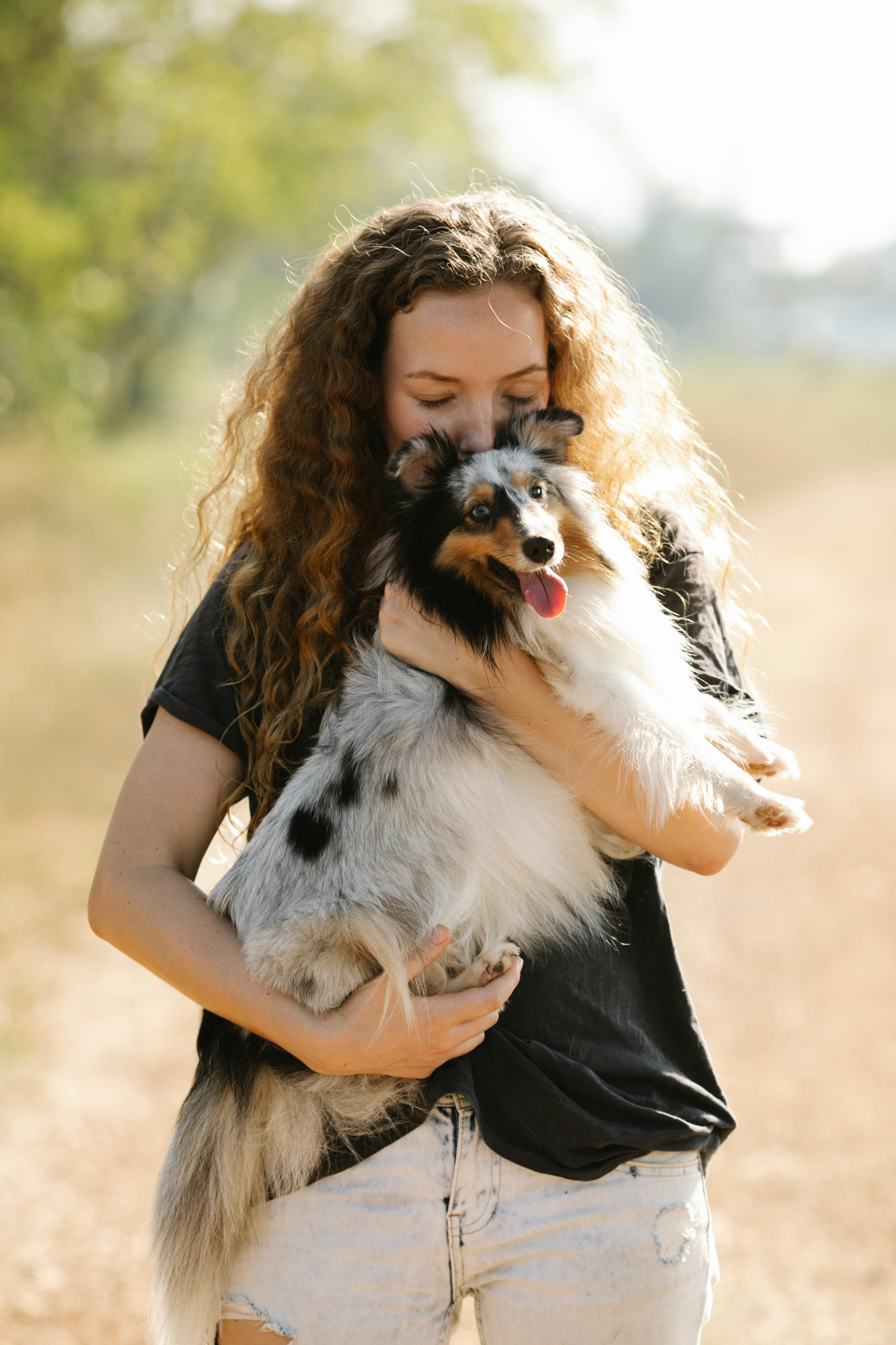 woman with sheltie in hands standing in countryside