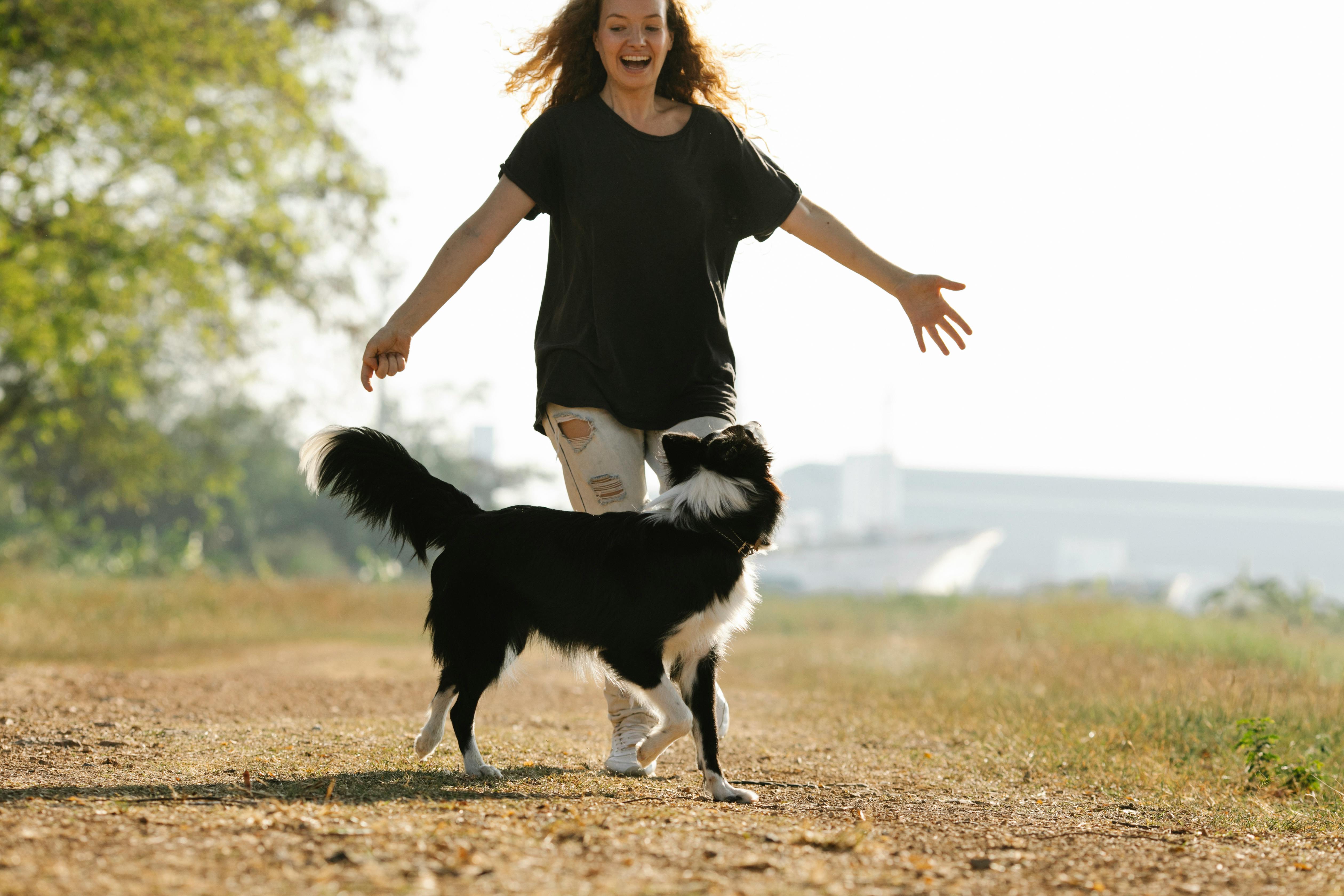 Happy woman running with Border Collie on rural road