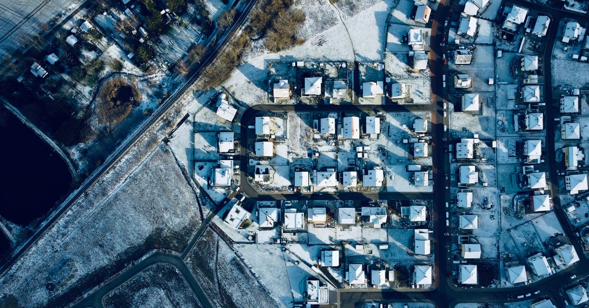 Aerial photograph showcasing a winter landscape of a snowy residential neighborhood.
