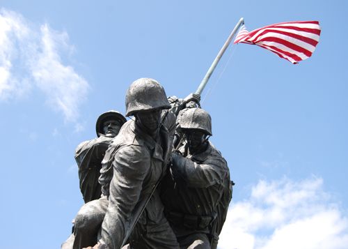 Free Dramatic view of the Iwo Jima Memorial under a blue sky, featuring US Marines raising the American flag. Stock Photo