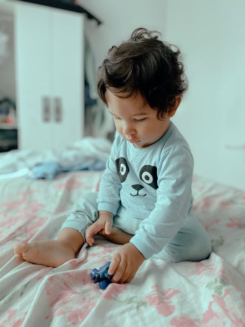 Free Selective Focus Photo of a Kid Playing with a Toy on the Bed Stock Photo