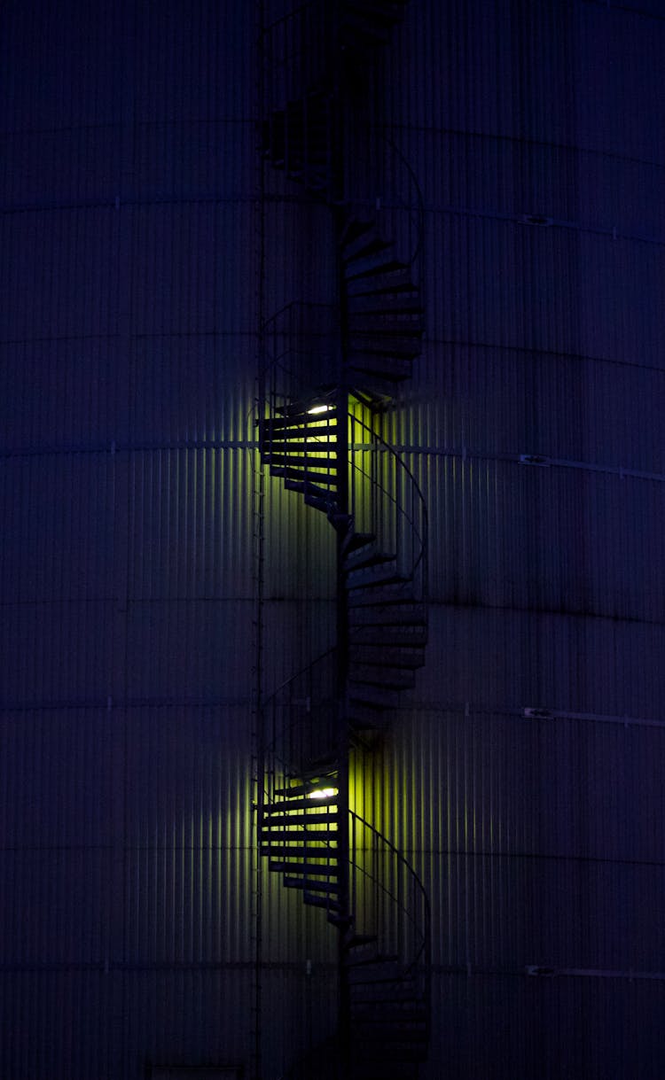 Spiral Stairs Against Building Wall At Night