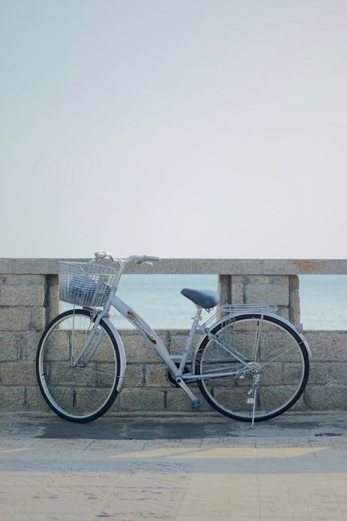 Free A vintage bicycle against a stone wall by the sea, perfect for travel and lifestyle themes. Stock Photo