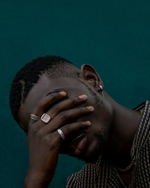 Close-Up Photo of a Man Covering His Face with His Hand with Rings