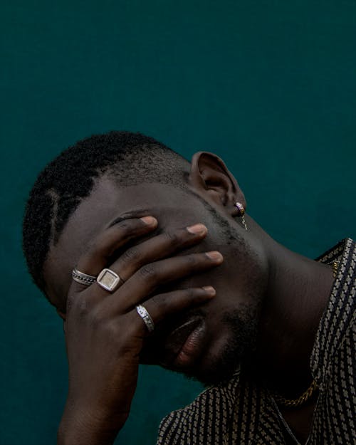 Close-Up Photo of a Man Covering His Face with His Hand with Rings