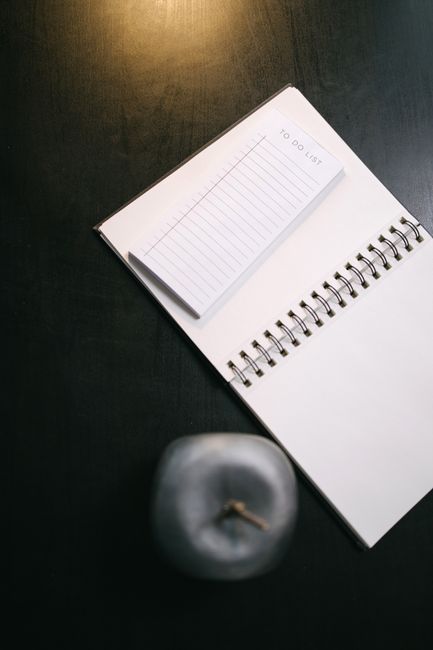 Open notebook with to-do list and silver apple on a dark table, perfect for productivity themes.