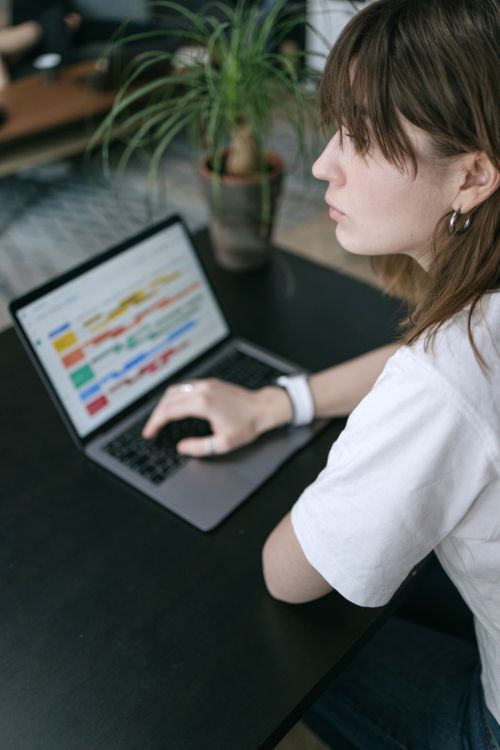 Free A woman studies data charts on her laptop at a modern indoor workspace. Stock Photo
