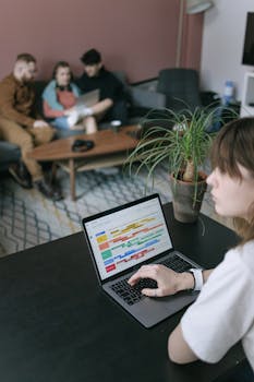 A woman working on a laptop during a team brainstorming session in a cozy office.