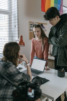Three young professionals brainstorming around a laptop in an office.