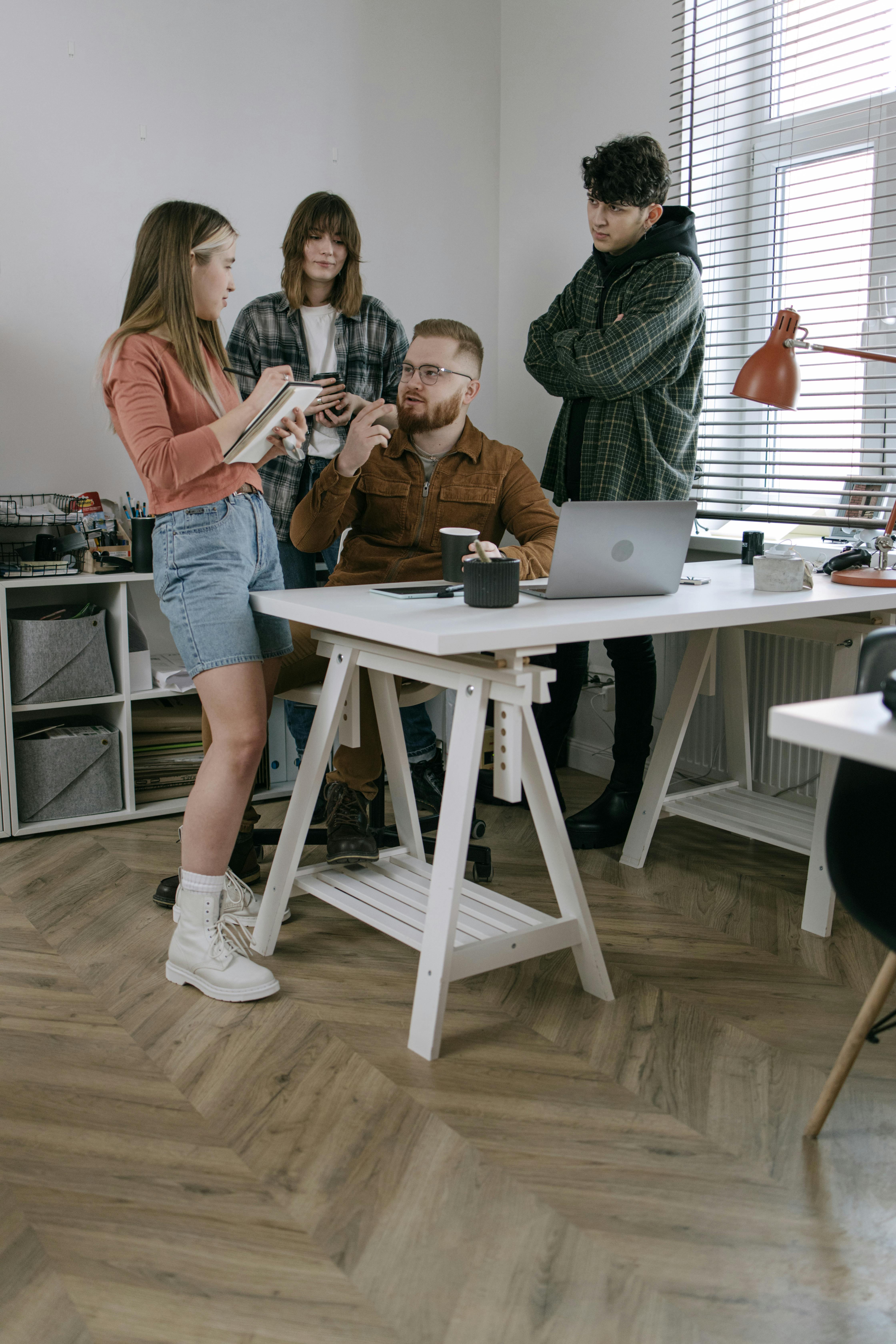 A group of young professionals engaged in a creative meeting in a modern office setting.