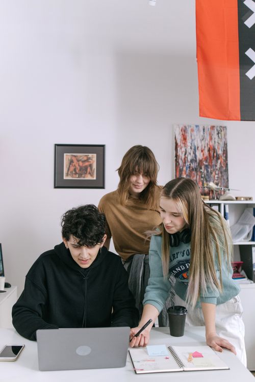 Free Three young adults working together in a creative office environment, discussing ideas and projects. Stock Photo